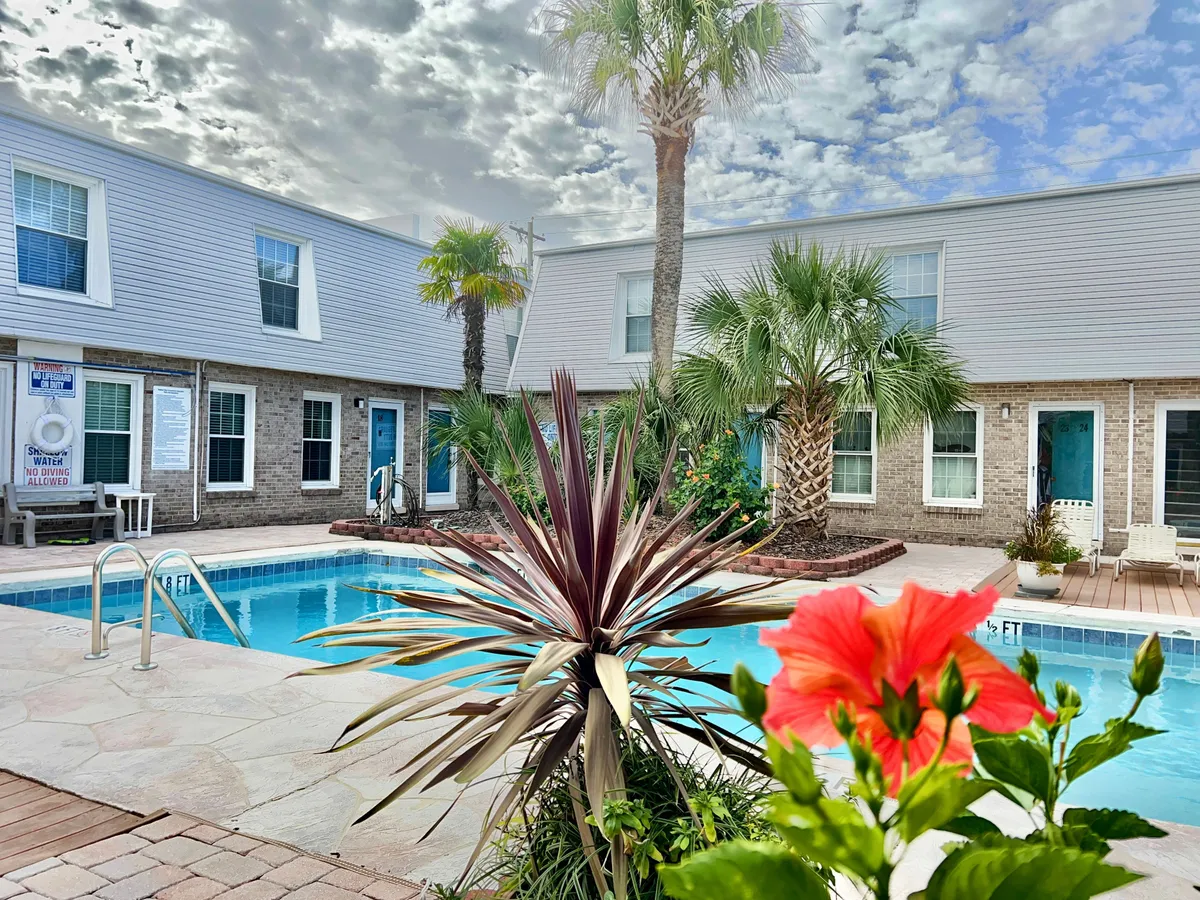 A cheerful view of the swimming pool accented by blooming colorful flowers, lush palm trees, and the villa’s exterior. The scene is relaxed and inviting with a sense of serenity and fresh air, ideal for enjoying both quiet mornings and lively afternoons.